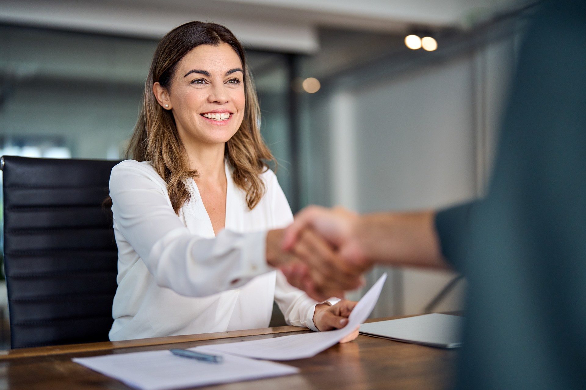 Feliz gerente de negocios de mediana edad apretando la mano en la reunión de la oficina.